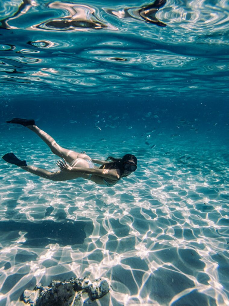 Woman snorkeling in Ibiza's crystal clear waters, showcasing aquatic serenity.