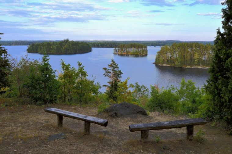 Scenic view of benches overlooking a serene Scandinavian lake with islands and lush trees, perfect for relaxation.