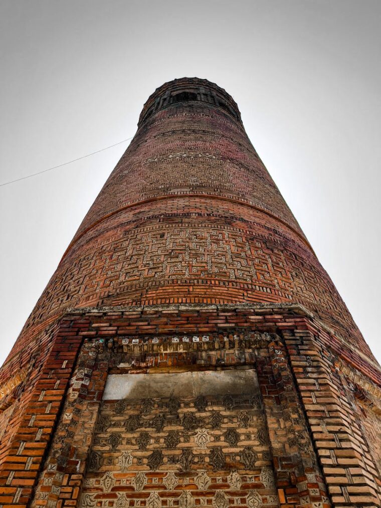 A detailed view of the ancient Uzgen Minaret in Osh Region, highlighting ornate brickwork.