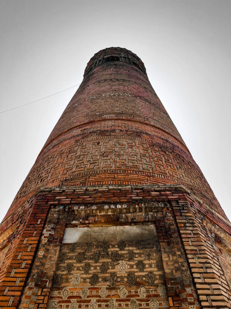 A detailed view of the ancient Uzgen Minaret in Osh Region, highlighting ornate brickwork.