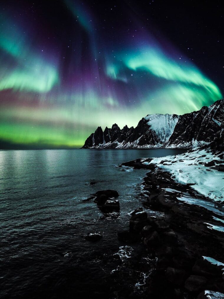 Majestic northern lights illuminate the snow-covered coast of Lenvik, Troms, Norway.