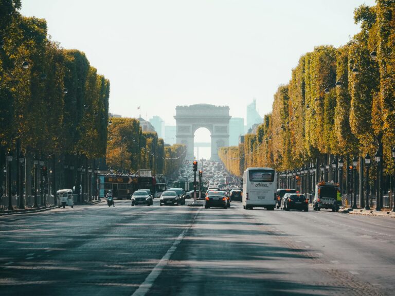 View of the Arc de Triomphe down a busy Champs Élysées in Paris, France, during fall.