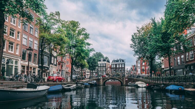 Charming view of an Amsterdam canal lined with bicycles, boats, and historic buildings.