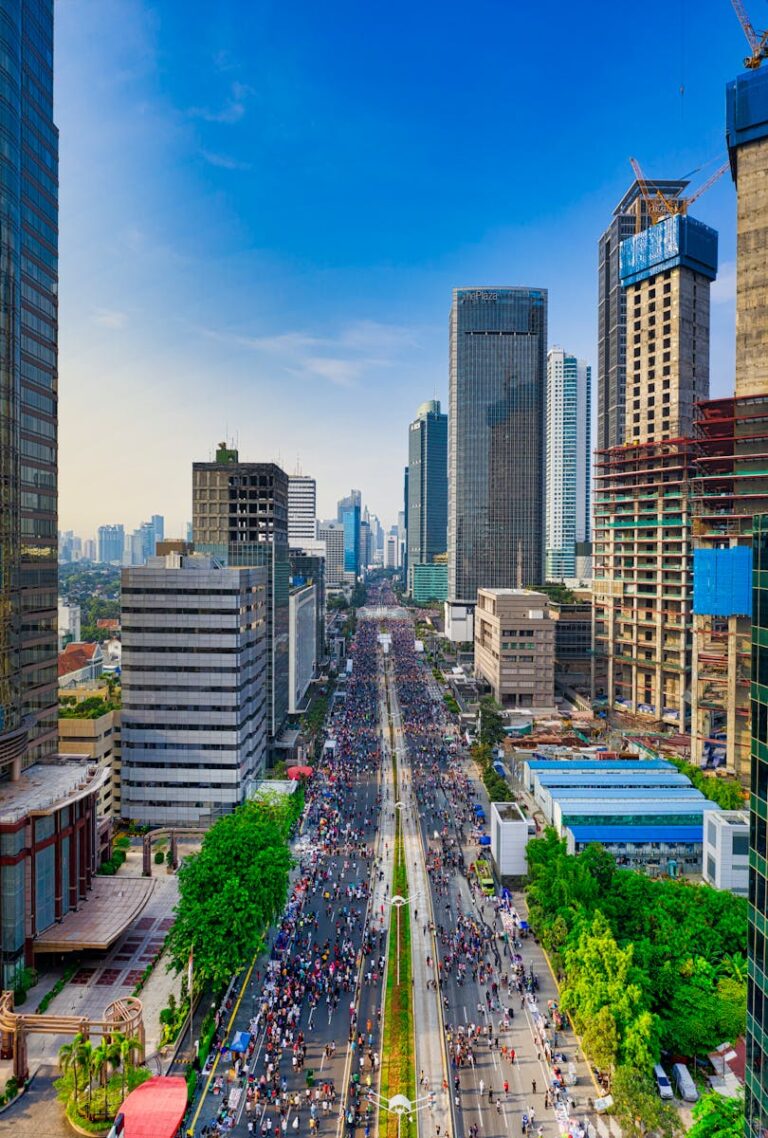 A dynamic aerial view of Jakarta showcasing modern skyscrapers and busy streets under a clear sky.