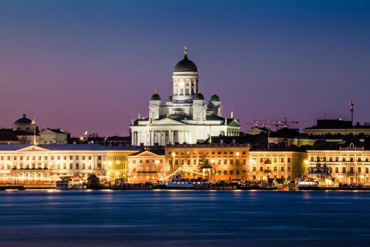 A stunning view of Helsinki Cathedral glowing at dusk with reflections on the water.