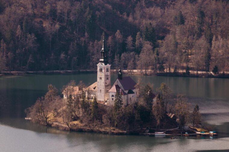 A stunning aerial view of the Church of the Assumption on Bled Island, Slovenia, surrounded by tranquil waters.