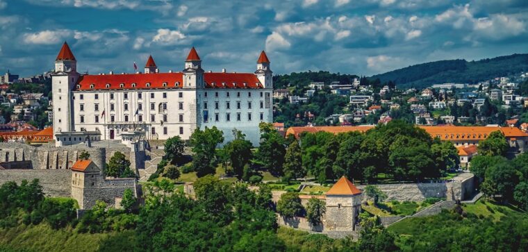 Beautiful panoramic view of Bratislava Castle towering over the Slovakian cityscape, surrounded by lush greenery.