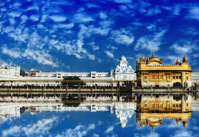 The Golden Temple, Harmandir Sahib, in Amritsar beautifully reflected in water with a vivid blue sky.