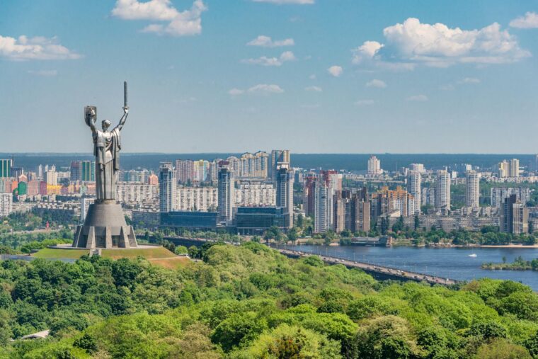 View of the Motherland Monument with Kyiv city and Dnieper River in the background on a sunny day.