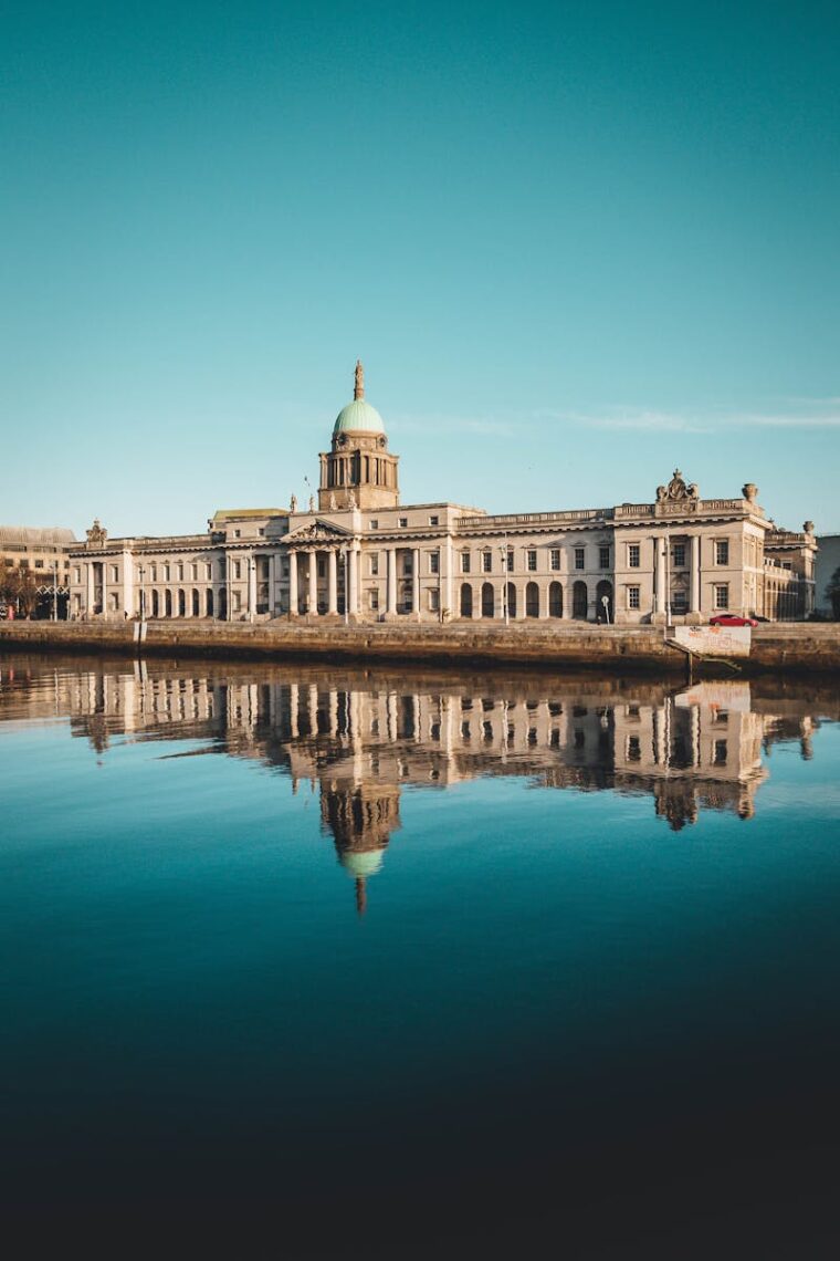 The Custom House in Dublin reflected on a calm river under a clear sky.