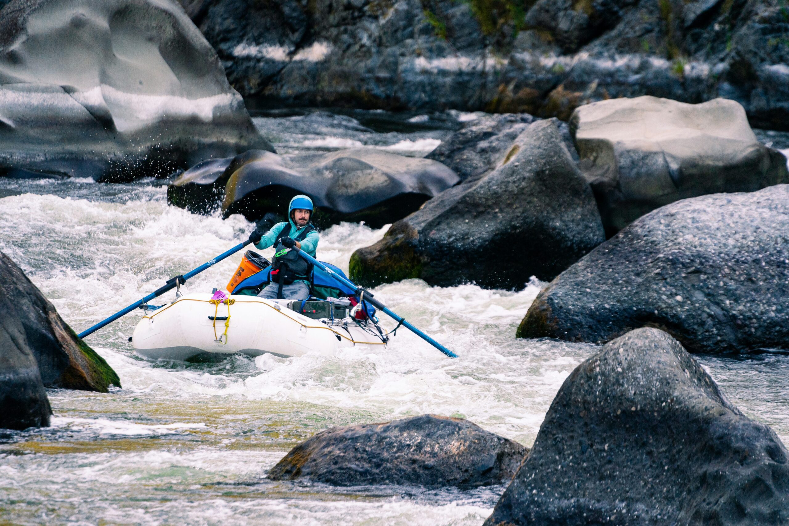 a man in a kayak on a river surrounded by rocks