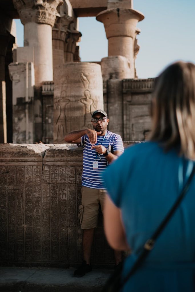 Tour guide explains historical ruins at an ancient temple to a visitor, showcasing cultural heritage.