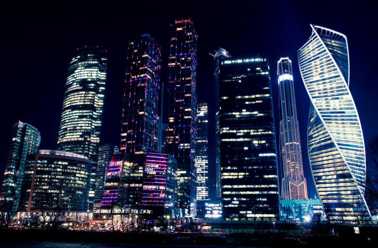 Illuminated night view of Moscow's modern skyscrapers, showcasing vibrant city lights and urban architecture.