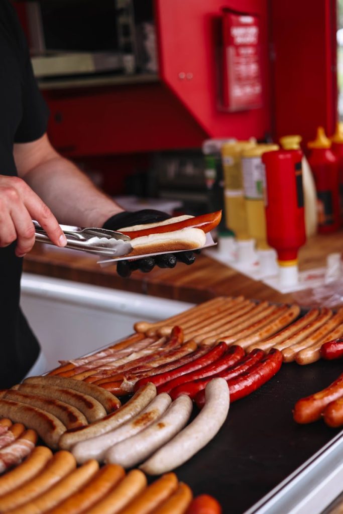 Delicious variety of grilled sausages being prepared at an outdoor food stand.