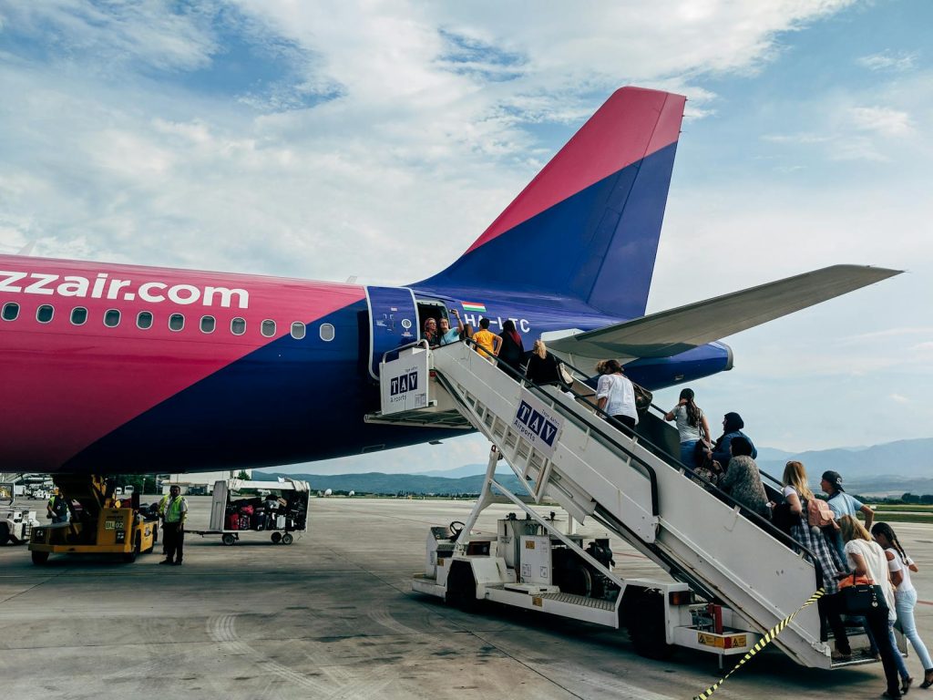 Travelers boarding a WizzAir Airbus A320 jet on a clear day at the airport.